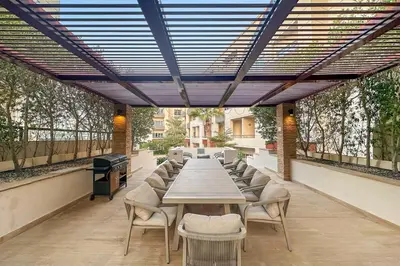 a long table and chairs on an outdoor patio at Pool View 1BR in Dubai Free Parking Gym Near Parks and Golf in Dubai