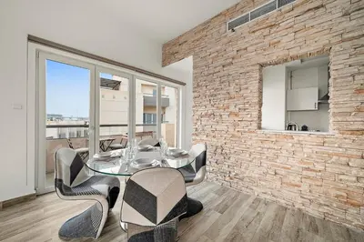 a dining room with a brick wall and a glass table and chairs at Pool View 1BR in Dubai Free Parking Gym Near Parks and Golf in Dubai