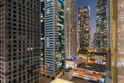 a city skyline at night with tall buildings at Stylish 1BR with Balcony Near Marina Mall, Pool & Free Parking in Dubai