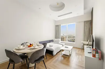 a living room with a table and chairs and a couch at Stylish 1BR with Balcony Near Marina Mall, Pool & Free Parking in Dubai