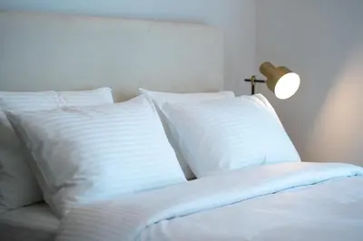 a bed with white pillows and a lamp on it at Keyrock Living - Binghatti Canal Luxury Stay in Dubai