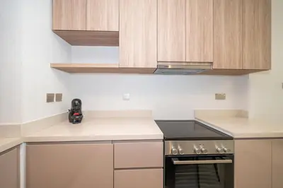a kitchen with wooden cabinets and a stove at Stylish 2BR Fully Furnished Unit at Business Bay in Dubai