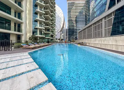 a large swimming pool in a city with tall buildings at Stylish 2BR Fully Furnished Unit at Business Bay in Dubai