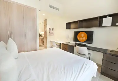 a bedroom with a white bed and a desk with a computer at EasyGo- Splendid Apartments in Al Meydan Living in Dubai