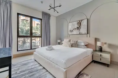 a white bedroom with a large bed and a desk at GuestReady - Downtown oasis with Burj Khalifa view in Dubai