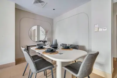 a dining room with a white table and chairs and a mirror at GuestReady - Downtown oasis with Burj Khalifa view in Dubai