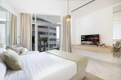 a white bedroom with a large bed and a tv at Panoramic! Burj Khalifa and Canal View! in Dubai