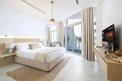 a white bedroom with a large bed and a tv at Panoramic! Burj Khalifa and Canal View! in Dubai
