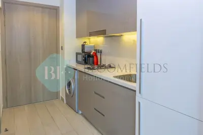 a kitchen with a counter top and a refrigerator at Bloomfields Cozy Stu Azizi Farhad in Dubai