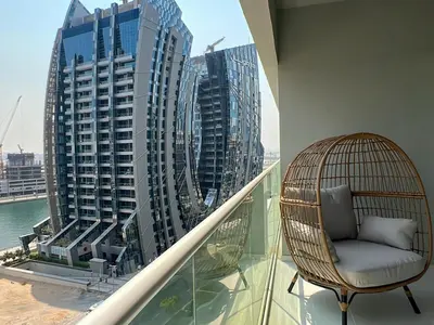 a chair on a balcony with a view of buildings at Keyrock Living - 1BR at Reva Residence with Lake View in Dubai