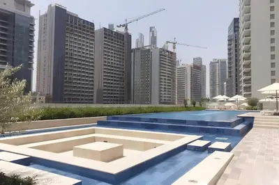 a pool in the middle of a city with tall buildings at Keyrock Living - 1BR at Reva Residence with Lake View in Dubai