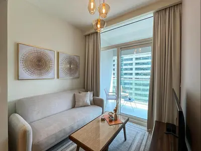 a living room with a couch and a large window at Keyrock Living - 1BR at Reva Residence with Lake View in Dubai