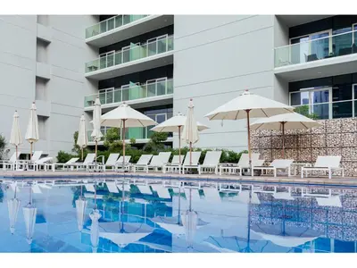 a swimming pool with umbrellas and chairs and a building at Luxury 1-Bedroom Apartment with Pool, Gym & Balcony in Business Bay in Dubai
