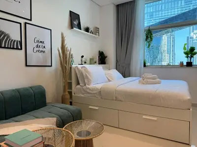 a bedroom with a bed and a couch and a window at ASHRI HH, Bohemian Style Condo in Downtown in Dubai