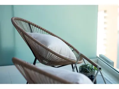 a rattan chair with a pillow sitting on a balcony at KeyRock Living - Stylish 1BR with Pool Access in Dubai