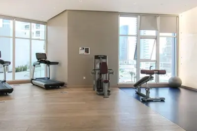 a gym with treadmills and ellipticals in a room with windows at HAVN - Studio in BusinessBay, 10mins to Dubai Mall in Dubai