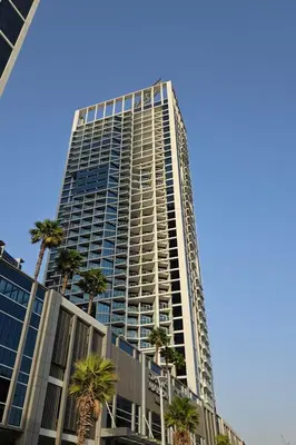 a tall building with palm trees in front of it at HAVN - Studio in BusinessBay, 10mins to Dubai Mall in Dubai