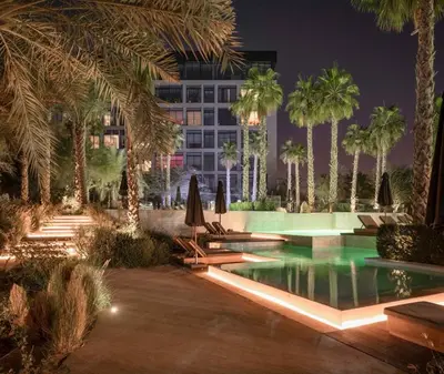 a resort pool with palm trees and a building at HAVN - Studio in KOA Canvas, Access to Nasab Dubai in Dubai
