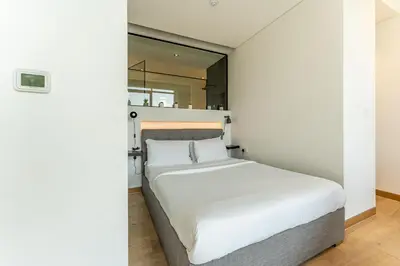 a bed in a room with a mirror at HAVN - Studio in KOA Canvas, Access to Nasab Dubai in Dubai