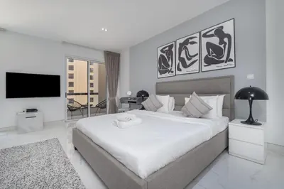 a bedroom with a large white bed and a tv at HAVN - Studio in Murjan JBR, 5mins to JBR Beach in Dubai