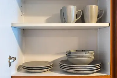 a shelf with plates and cups and bowls at Stylish JLT Studio Lakeview Metro FrontMarina in Dubai