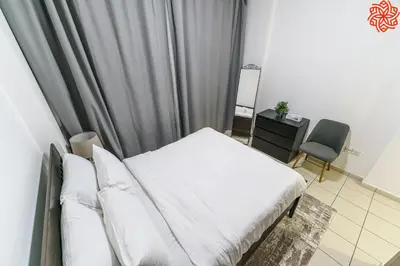 a bedroom with a bed and a chair and a window at Calm 1bdr apartment in JVC in Dubai