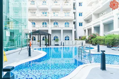 a hotel swimming pool in front of a building at Calm 1bdr apartment in JVC in Dubai