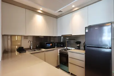 a kitchen with white cabinets and a black refrigerator at Livbnb-Perfect 1BR Retreat in the Heart of JVC in Dubai