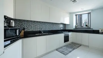 a white kitchen with a sink and a microwave at 3BR Paramount Downtown - Burj Khalifa View in Dubai