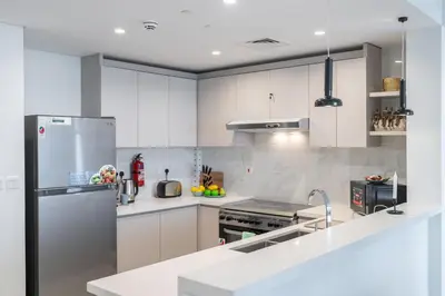 a kitchen with white cabinets and a stainless steel refrigerator at Vogue Al Wasl 1 Residences Near Zabeel Park and World Trade Centre, Two Bedroom Apartment with Balcony offering Dubai Frame and City View, Access to all Amenities, Walkable to Max Fashion Metro Station in Dubai