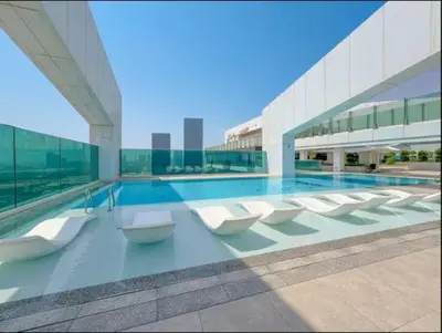 a large building with a swimming pool with white chairs at Vogue Al Wasl 1 Residences Near Zabeel Park and World Trade Centre, Two Bedroom Apartment with Balcony offering Dubai Frame and City View, Access to all Amenities, Walkable to Max Fashion Metro Station in Dubai