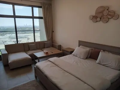 a bedroom with a bed and a couch and a window at Studio in Business bay, Metro! in Dubai