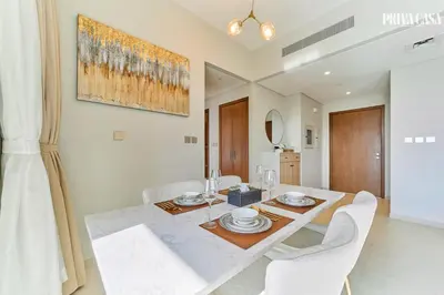 a dining room with a table and white chairs at PRIVA CASA - Luxurious 2BR Vida Creek Beach - Beach access in Dubai