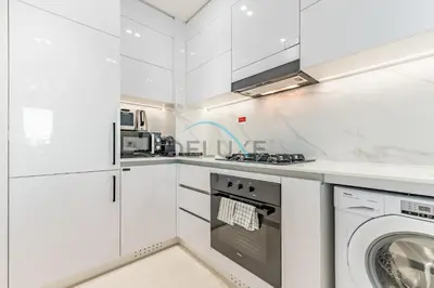 a white kitchen with a washer and dryer at City Views 1BR Close to Golf Course & Attractions, Binghatti Venus, Jumeirah Village Circle by Deluxe Holiday Homes in Dubai