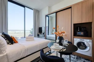 a hotel room with a bed and a table and a washing machine at Cosy Studio in Binghatti House in Dubai