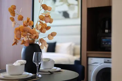 a table with a vase of flowers and two cups at Cosy Studio in Binghatti House in Dubai