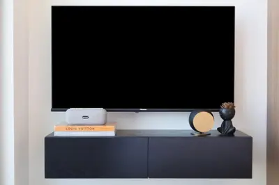 a flat screen tv sitting on top of a black cabinet at Cosy Studio in Binghatti House in Dubai