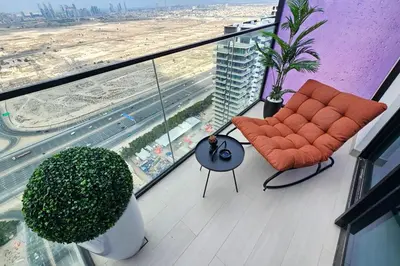 a balcony with an orange chair and a view of a city at Stunning Studio in Binghatti House in Dubai