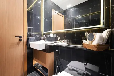 a black tiled bathroom with two sinks and a toilet at Stunning Studio in Binghatti House in Dubai