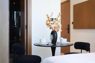 a table with a vase of flowers and two cups at Stunning Studio in Binghatti House in Dubai