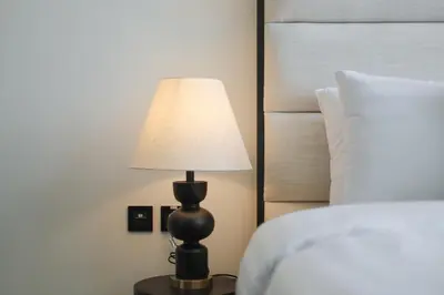 a lamp sitting on a table next to a bed at Stunning Studio in Binghatti House in Dubai