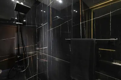 a bathroom with a black tiled shower with a towel at Stunning Studio in Binghatti House in Dubai