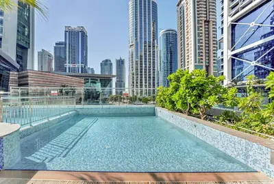 a swimming pool with a city skyline in the background at Waves - Modern Studio with Stunning Lake Views in JLT in Dubai