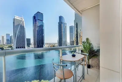 a balcony with a table and chairs and a pool at Waves - Modern Studio with Stunning Lake Views in JLT in Dubai