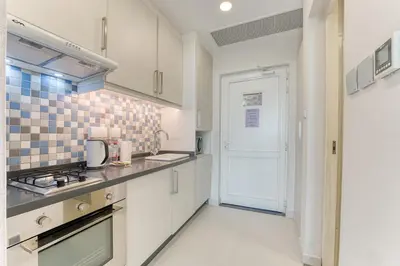 a kitchen with white cabinets and a stove at Starfish Palm Views Studio in Dubai
