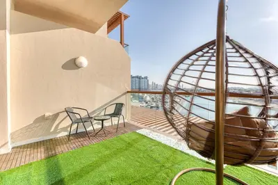 a balcony with a table and chairs and a metal orb at Starfish Palm Views Studio in Dubai