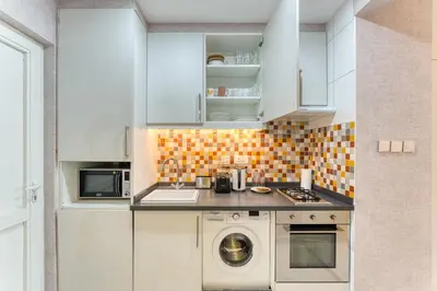 a kitchen with white cabinets and a washing machine at Octopus - Iconic Palm Studio With Views in Dubai