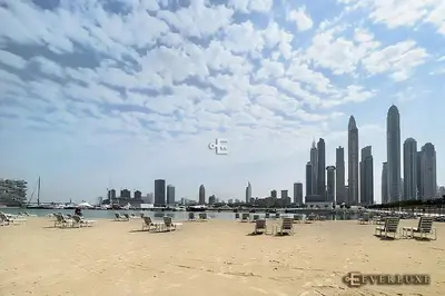 a beach with chairs and a city in the background at Chill 1br W Beach Views & Private Beach Access in Dubai
