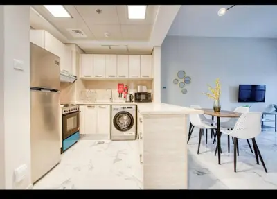 a kitchen with white cabinets and a table with chairs at 012 - Dubai South in Dubai