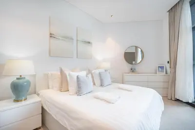 a white bedroom with a bed with white sheets and pillows at Water Front Apartment, Burj Khalifa Views in Dubai